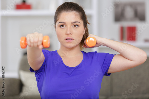 serious young woman doing dumbbells