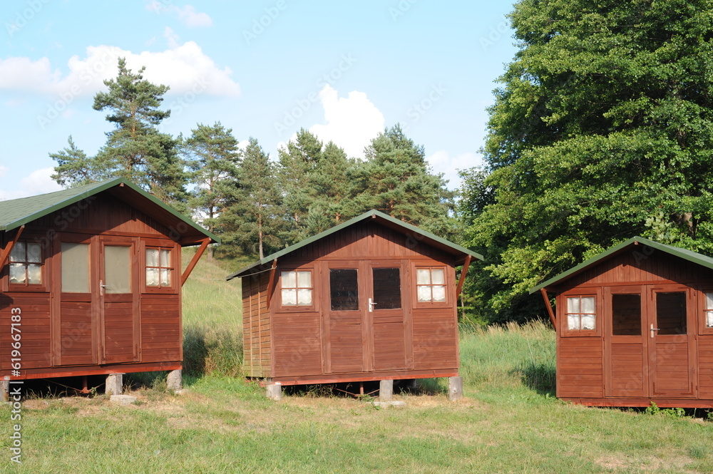 Wooden cabin or lodge as summerhouse in a forest with green grass on a sunny summer day Wooden cabin or lodge as summerhouse in a forest with green grass on a sunny summer day
