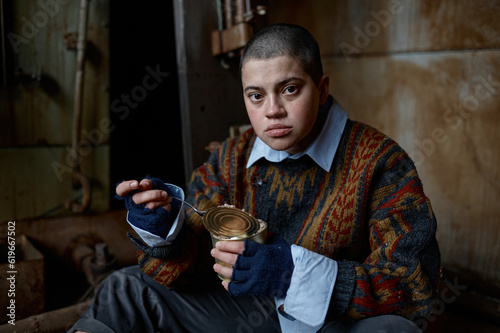 Hungry homeless castoff young woman eating canned food photo