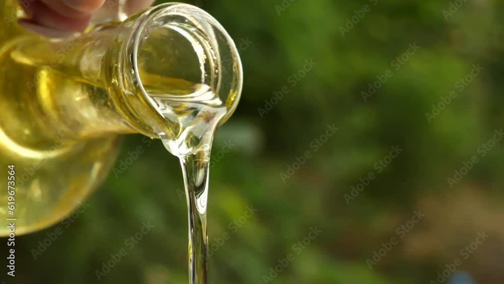 slow motion shot of extra virgin olive oil being poured from a clear glass bottle slow motion shot of extra virgin olive oil being poured from a clear glass bottle