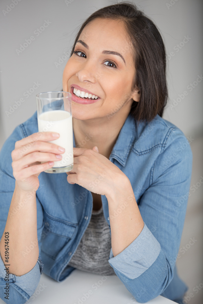 young woman holding a glass of milk smiling young woman holding a glass of milk smiling
