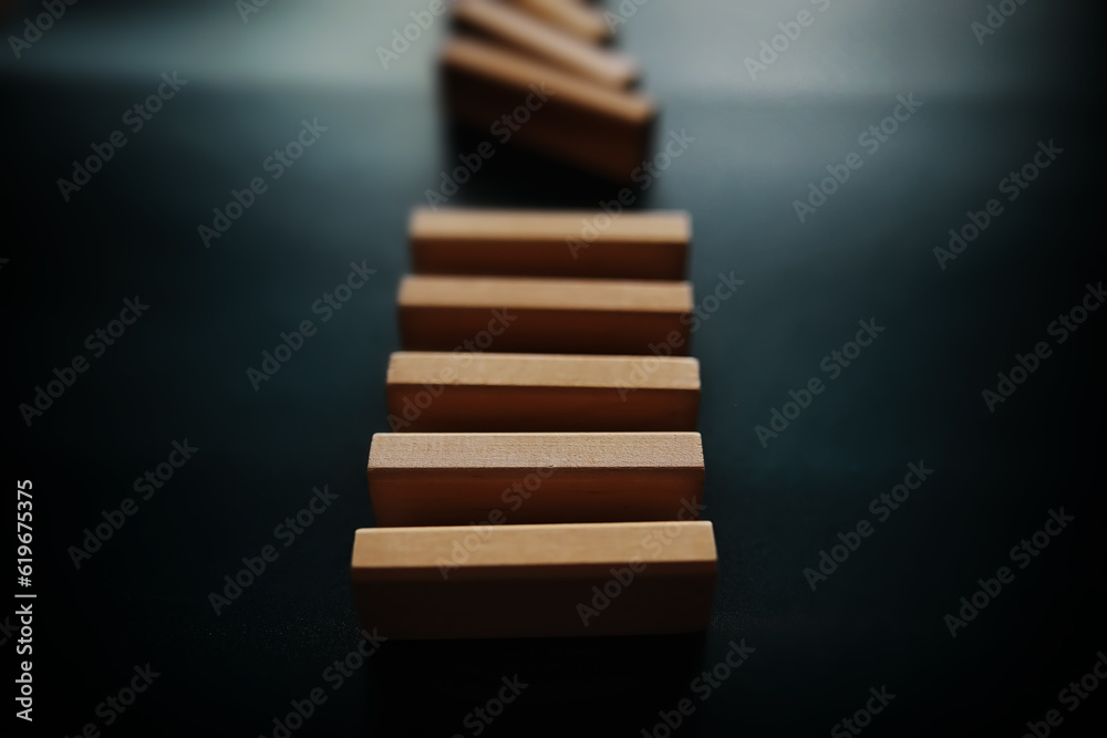 domino effect concept with wooden tiles blocked by hourglass with background domino effect concept with wooden tiles blocked by hourglass with background
