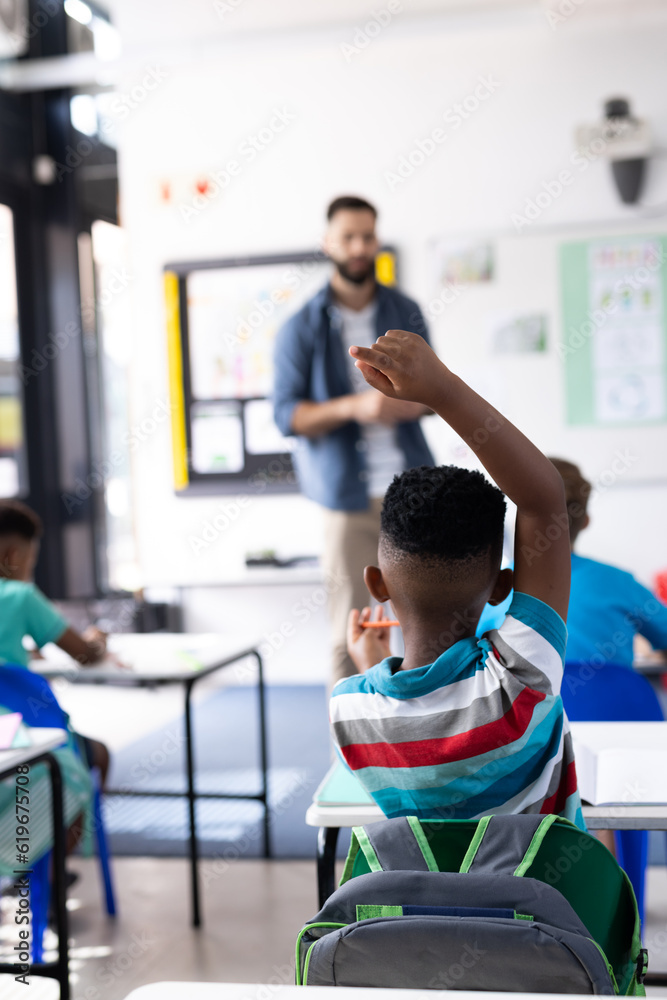 Vertical of african american boy raising hand in diverse elementary school class, copy space Vertical of african american boy raising hand in diverse elementary school class, copy space