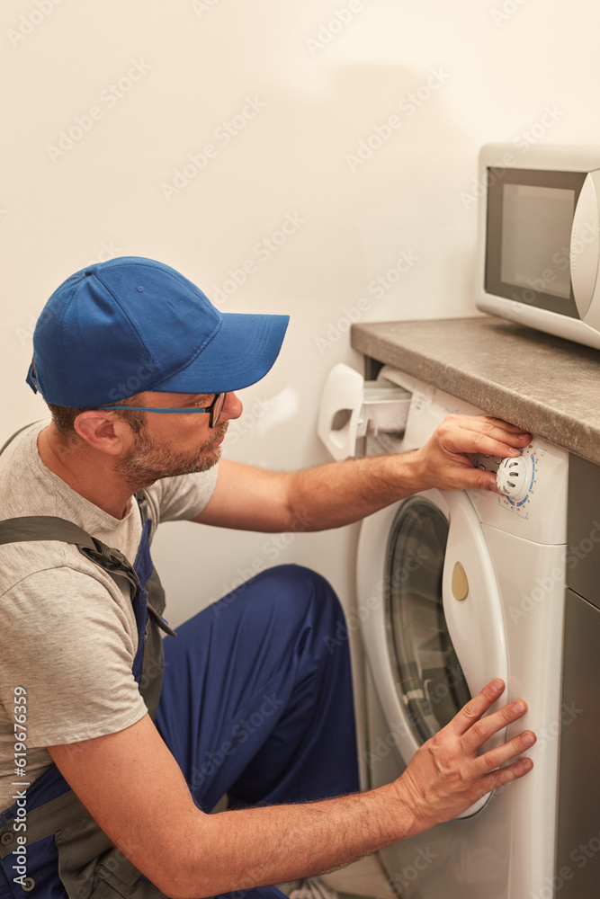 Handyman fixing broken washing machine in the apartment. Handyman fixing broken washing machine in the apartment.