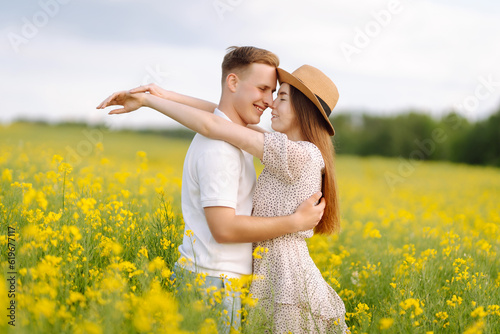Young couple in love walks through a rapeseed field. Happy men and women in style enjoy the time spent together. The concept of love, test, relationship. © maxbelchenko