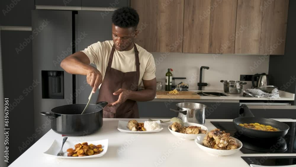 Young black man serving tomato sauce on fried chicken mince, plantain and rice on a plate in a kitchen. Young black man serving tomato sauce on fried chicken mince, plantain and rice on a plate in a kitchen.