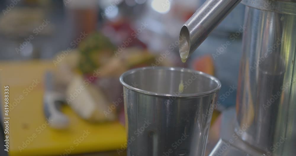 Close Up Rack Focus of a Juicer Dripping Juice into a Cup Close Up Rack Focus of a Juicer Dripping Juice into a Cup