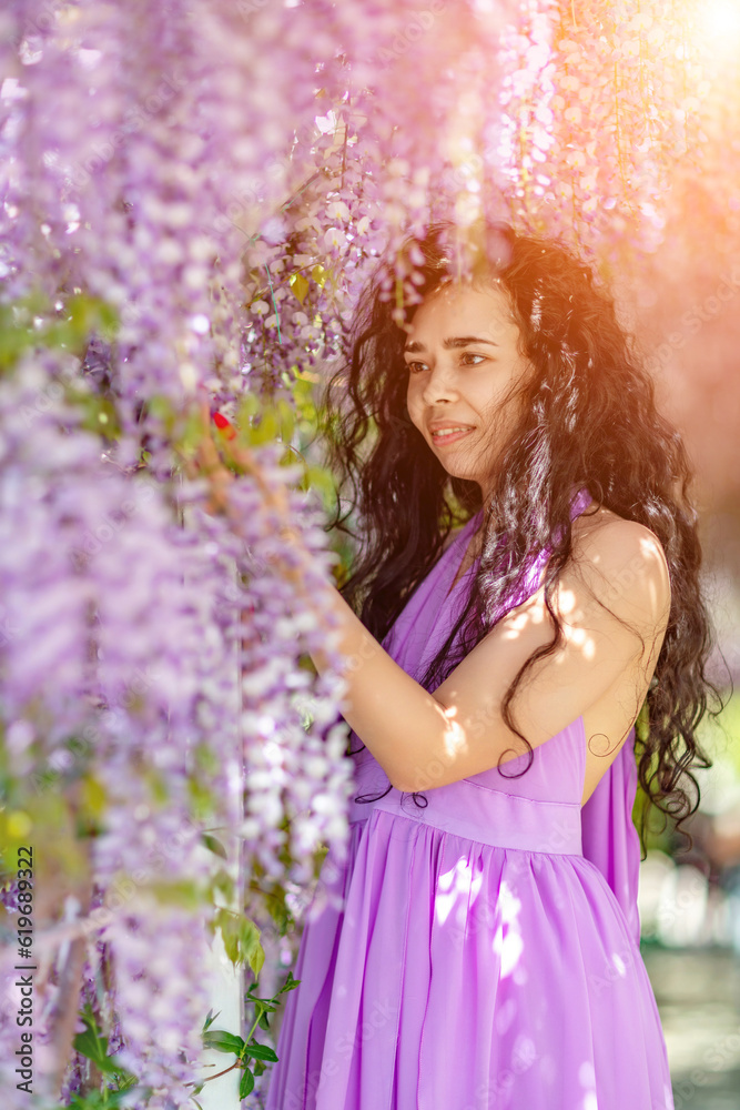 Woman wisteria lilac dress. Thoughtful happy mature woman in purple dress surrounded by chinese wisteria Woman wisteria lilac dress. Thoughtful happy mature woman in purple dress surrounded by chinese wisteria