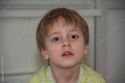 A cute boy in a striped T-shirt. Portrait of a blond boy in a natural setting. The face expresses natural emotions.
