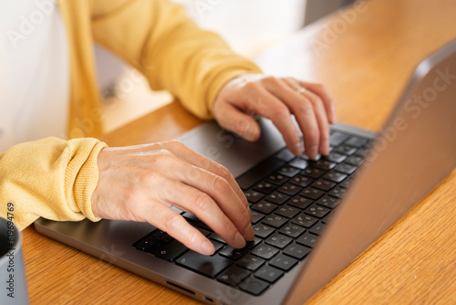 ノートパソコンをタイピングしているシニア女性