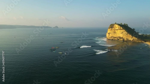 Panoramic aerial view of Gerupuk surf spot with surfers riding the wave, cliffs in the middle of the Bali sea photo