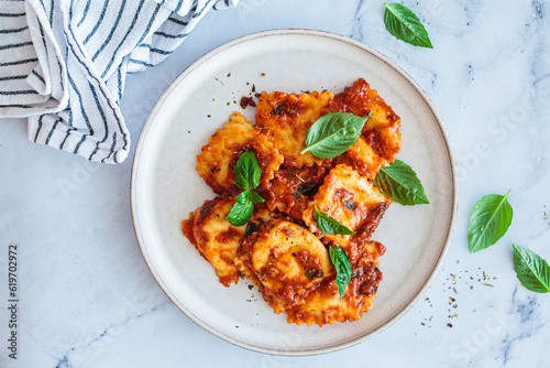 Ravioli with ricotta, tomato sauce and basil, white marble background. photo