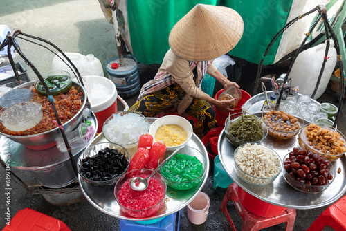 Fototapeta Naklejka Na Ścianę i Meble -  A Vietnamese woman preparing street food in a small street cafe.