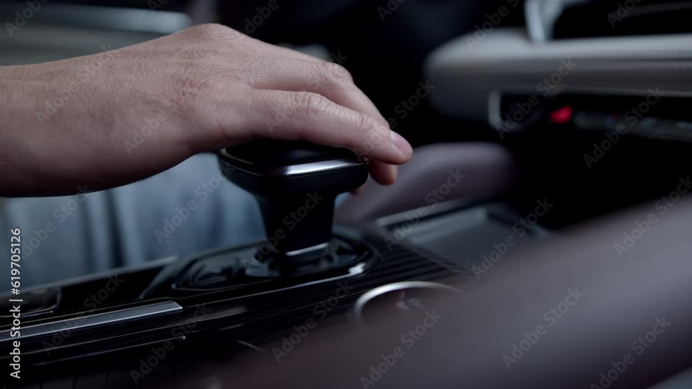 Close up man hand shift automatic transmission of expensive premium car inside cabin. interior of beautiful SUV with brown and white leather upholstery. Close up man hand shift automatic transmission of expensive premium car inside cabin. interior of beautiful SUV with brown and white leather upholstery.