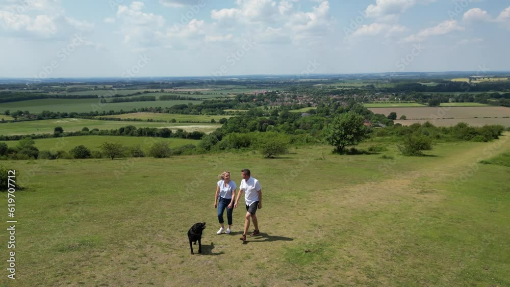Drone Shot Of Mature Couple Walking With Pet Dog Through Beautiful English Countryside In Oxfordshire England UK Drone Shot Of Mature Couple Walking With Pet Dog Through Beautiful English Countryside In Oxfordshire England UK