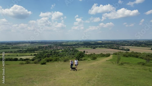 Drone Shot Of Mature Couple Walking With Pet Dog Through Beautiful English Countryside In Oxfordshire England UK