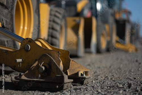 Fototapeta Naklejka Na Ścianę i Meble -  A lineup of heavy equipment is waiting at a construction site. One of the machines has its outrigger pad extended, helping to hold it in place.