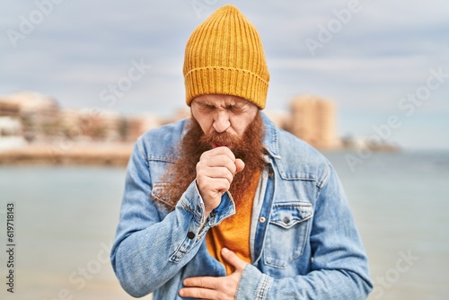 Young redhead man coughing at seaside
