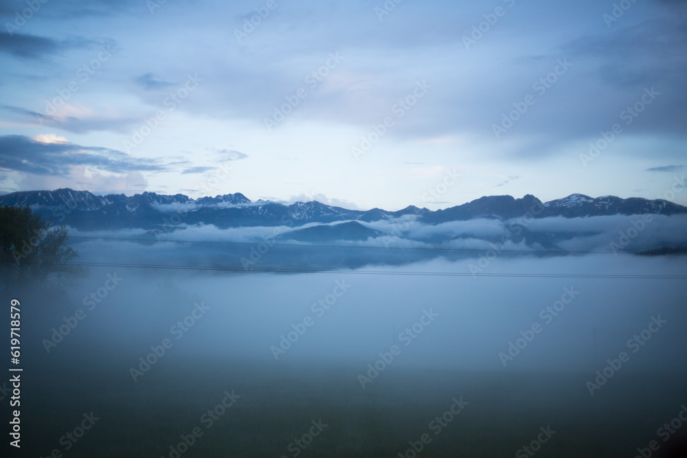 Cloudy weather in the clouds. The peaks of the Tatra Mountains through floating white clouds.