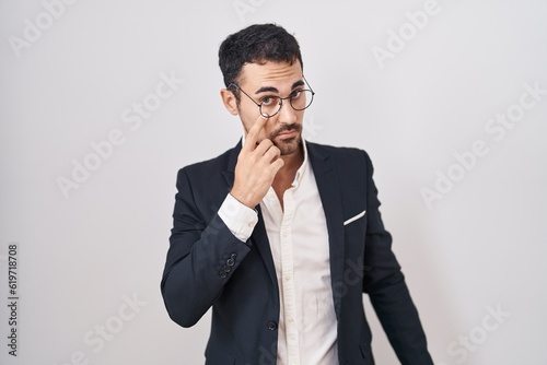 Handsome business hispanic man standing over white background pointing to the eye watching you gesture, suspicious expression