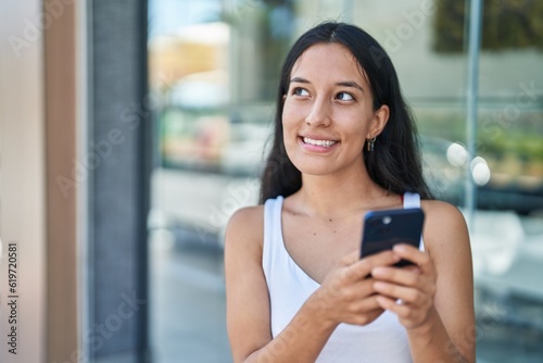 Young beautiful hispanic woman smiling confident using smartphone at street