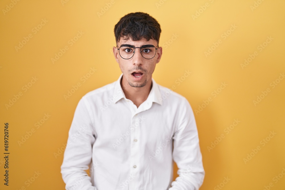 Young hispanic man standing over yellow background afraid and shocked with surprise and amazed expression, fear and excited face. Young hispanic man standing over yellow background afraid and shocked with surprise and amazed expression, fear and excited face.