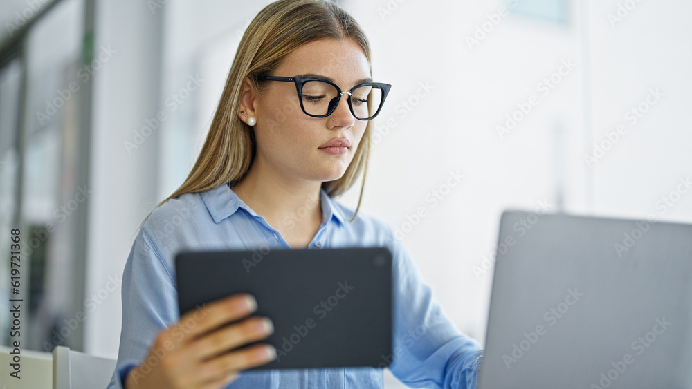 Young blonde woman business worker using laptop and touchpad at office Young blonde woman business worker using laptop and touchpad at office