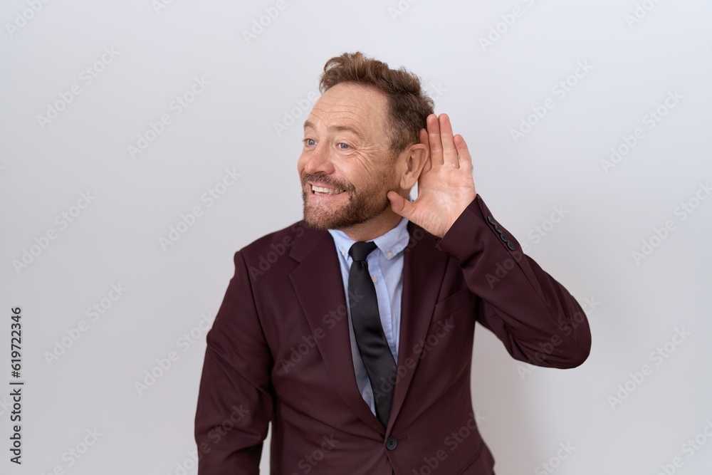 Middle age business man with beard wearing suit and tie smiling with hand over ear listening an hearing to rumor or gossip. deafness concept. Middle age business man with beard wearing suit and tie smiling with hand over ear listening an hearing to rumor or gossip. deafness concept.