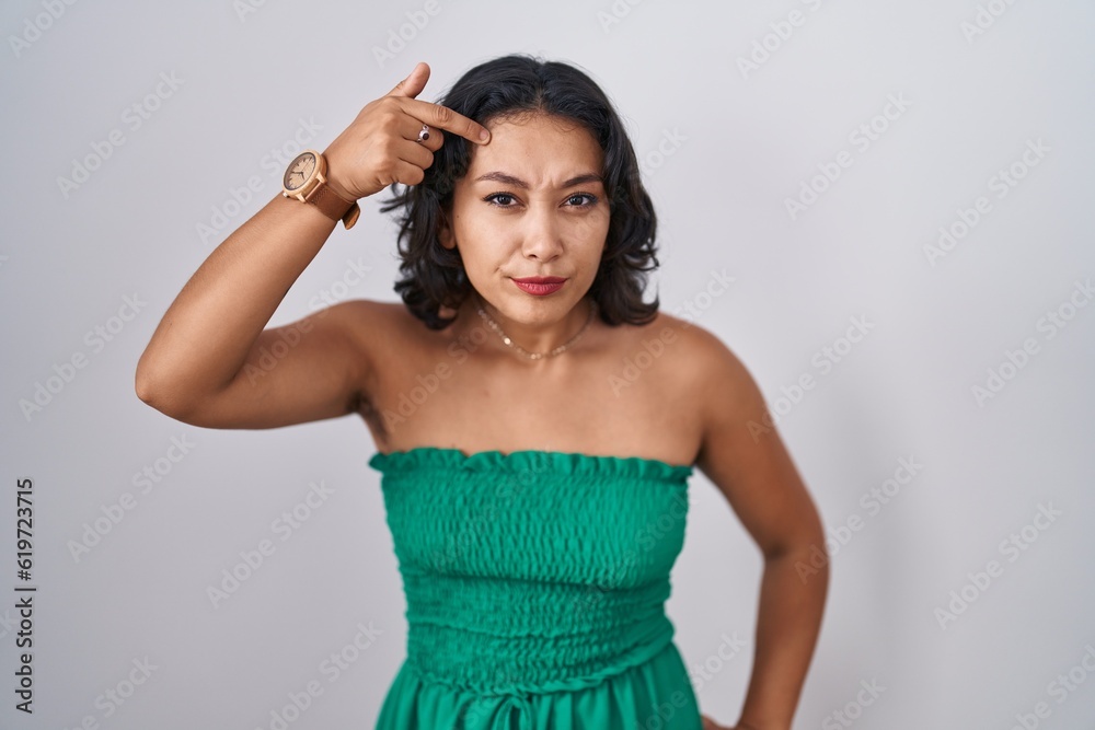 Young hispanic woman standing over isolated background pointing unhappy to pimple on forehead, ugly infection of blackhead. acne and skin problem Young hispanic woman standing over isolated background pointing unhappy to pimple on forehead, ugly infection of blackhead. acne and skin problem