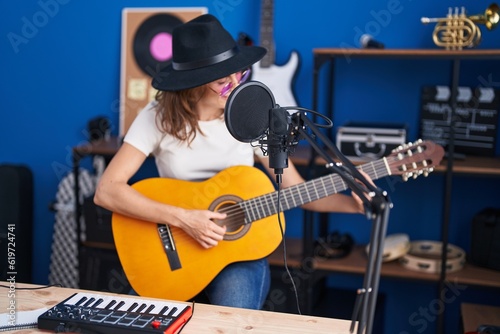 Young woman musician singing song playing classical guitar at music studio