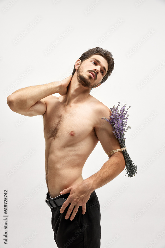 Fototapeta premium Portrait of handsome young dark-haired man posing isolated over studio background. Male natural beauty concept.