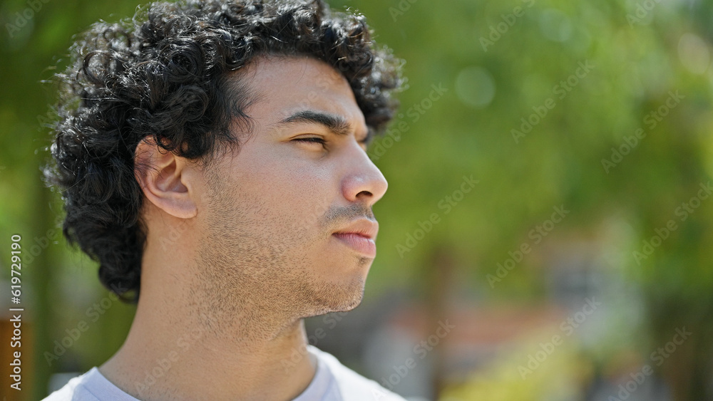 Young latin man looking to the side with serious expression at park Young latin man looking to the side with serious expression at park