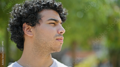 Young latin man looking to the side with serious expression at park