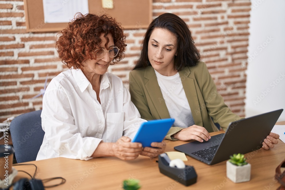 Two women business workers using laptop and touchpad working at office Two women business workers using laptop and touchpad working at office