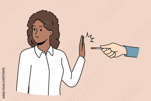 African American woman refusing to smoke making prohibition gesture near hand with cigarette made of tobacco and nicotine. Ethnic girl wants to quit smoke and fight addictive bad habits