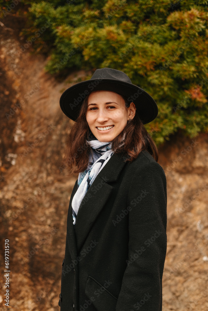 Close up vertical portrait of smiling young woman wearing black hat and coat outdoors. Close up vertical portrait of smiling young woman wearing black hat and coat outdoors.