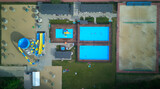 Aerial top down view of swimming pools and football and valley court in the resort.