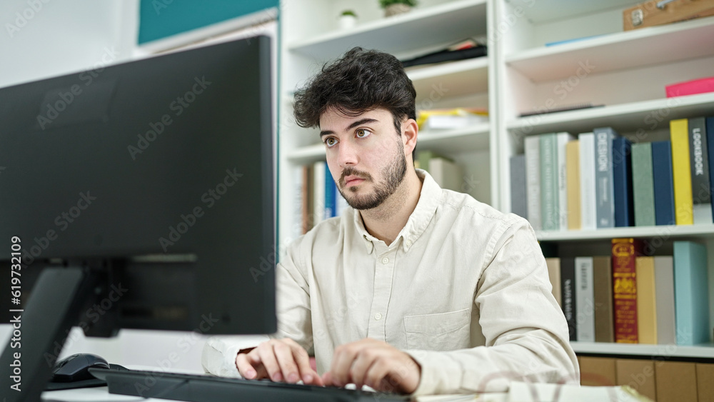 Young hispanic man student using computer studying at library university Young hispanic man student using computer studying at library university