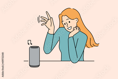 Woman uses wireless speaker with voice control to listen to music or communicate with virtual interlocutor. Wireless speaker for smart home and IOT technology near young smiling girl