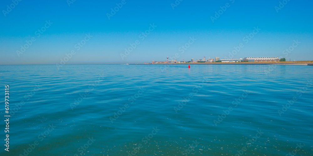 Sand beach along a sea under a dark blue cloudy sky in bright sunlight in summer, Zeeland, the Netherlands, June, 2023