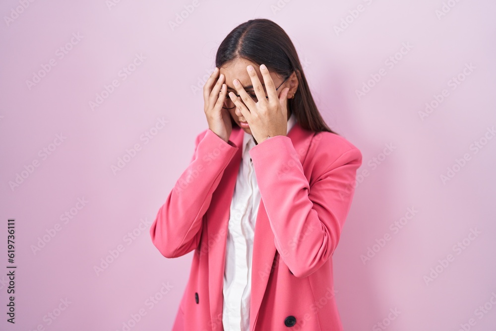 Young hispanic woman wearing business clothes and glasses with sad expression covering face with hands while crying. depression concept. Young hispanic woman wearing business clothes and glasses with sad expression covering face with hands while crying. depression concept.