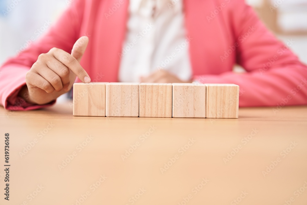 Young beautiful hispanic woman business worker sitting on table with wooden cubes at office Young beautiful hispanic woman business worker sitting on table with wooden cubes at office