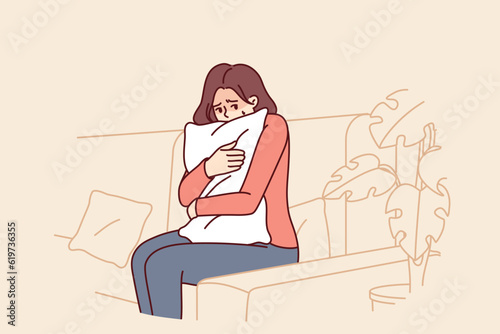 Frightened woman hugging pillow sitting on couch feeling fear and depressed psychological state. Frightened teen girl is afraid to be alone and sad because of breaking up with boyfriend