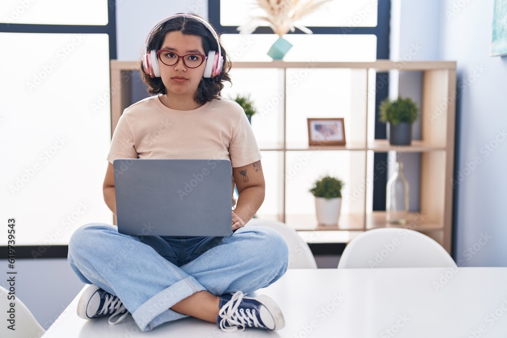 Young hispanic woman using laptop sitting on the table wearing headphones skeptic and nervous, frowning upset because of problem. negative person. Young hispanic woman using laptop sitting on the table wearing headphones skeptic and nervous, frowning upset because of problem. negative person.