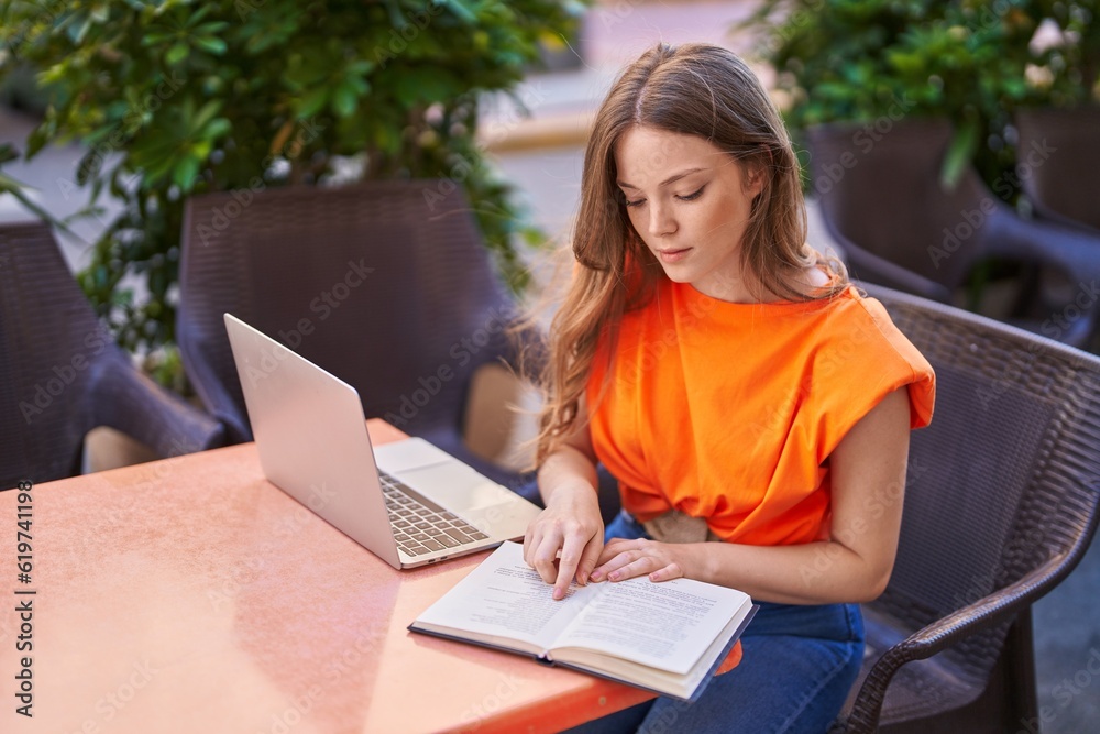 Young woman sitting on table studying at coffee shop terrace