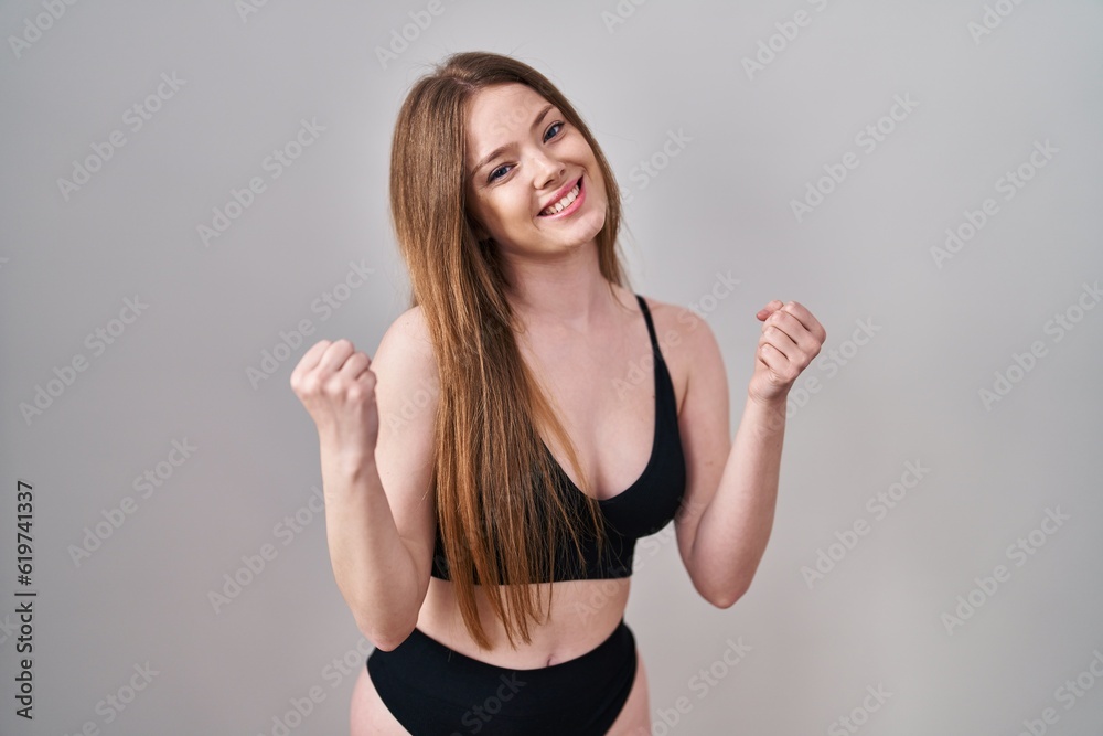 Fototapeta premium Young caucasian woman wearing lingerie very happy and excited doing winner gesture with arms raised, smiling and screaming for success. celebration concept.