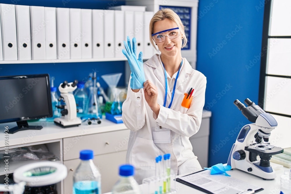 Young blonde woman scientist standing with arms crossed gesture at laboratory