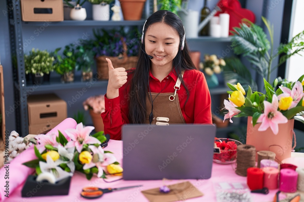 Young asian woman working at florist shop doing video call smiling happy and positive, thumb up doing excellent and approval sign Young asian woman working at florist shop doing video call smiling happy and positive, thumb up doing excellent and approval sign