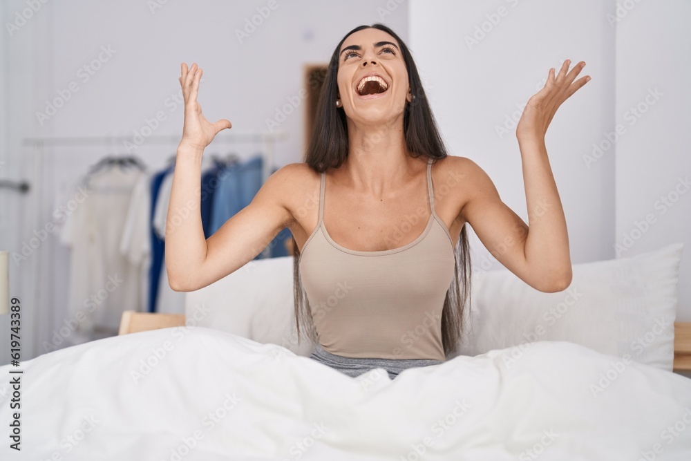 Young brunette woman in the bed at home celebrating mad and crazy for success with arms raised and closed eyes screaming excited. winner concept Young brunette woman in the bed at home celebrating mad and crazy for success with arms raised and closed eyes screaming excited. winner concept