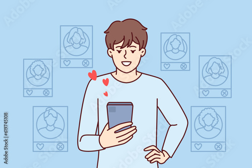 Man uses dating app on mobile phone and looks through profiles of women likes. Guy with smartphone visits dating sites on internet and is looking for girlfriend for flirting and romantic relationships
